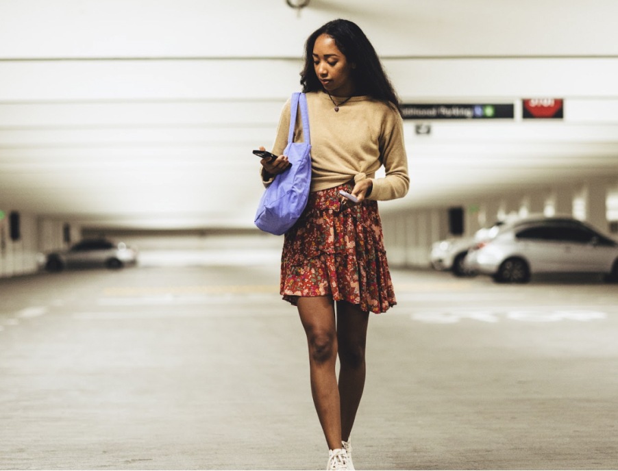 A teen walking in a parking garage while looking at her phone