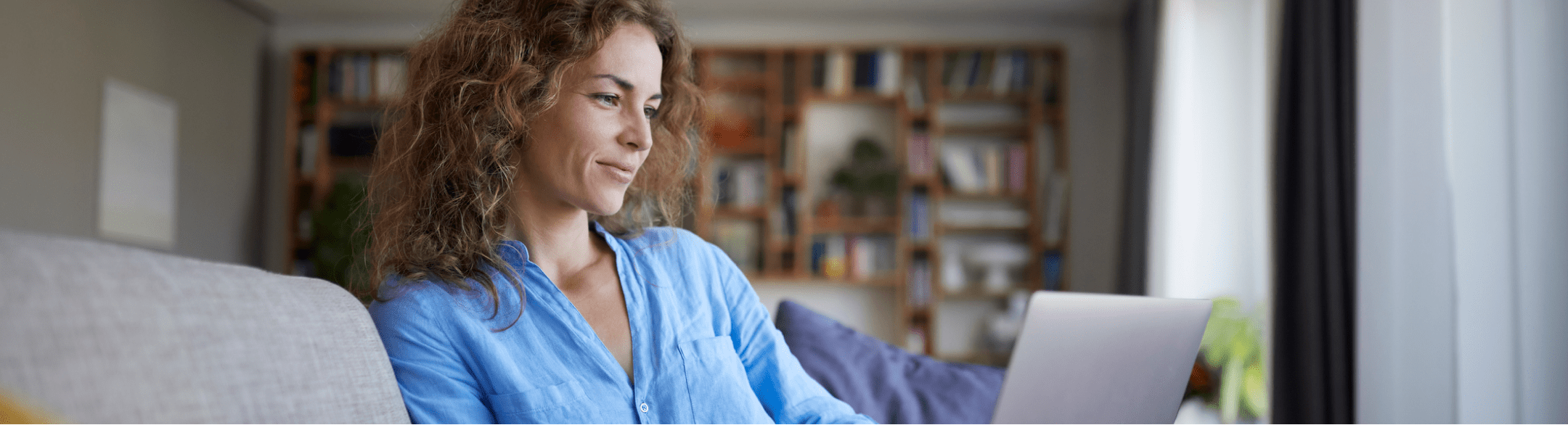 Woman looking at laptop while sitting on a couch