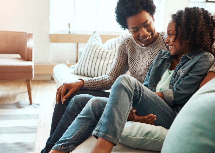 Mother and daughter laughing on a couch