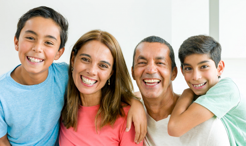 Family of four posing and smiling for a picture