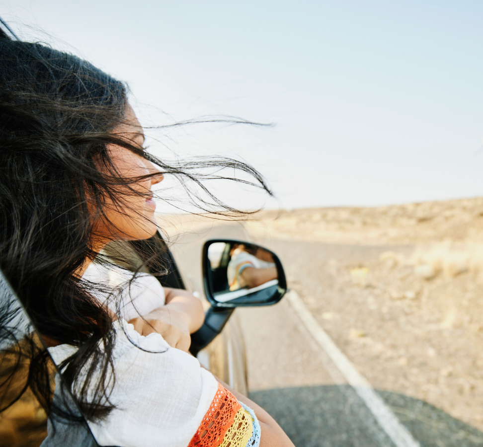 Girl in car with her head out of the window