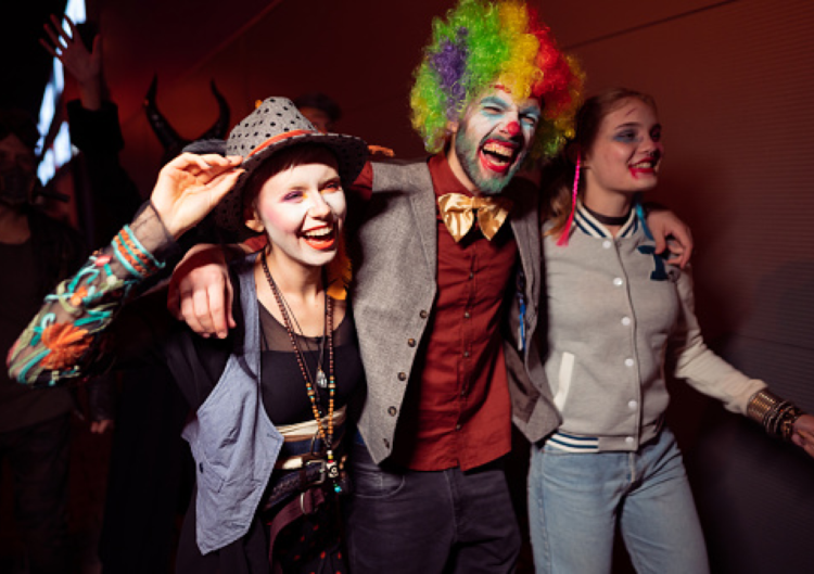 Three people in costume on Halloween laughing with their arms around each other