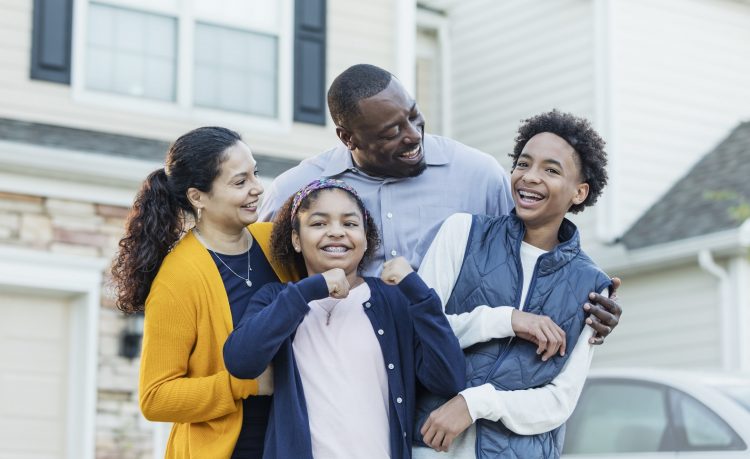 4 person family standing in from of a suburban house