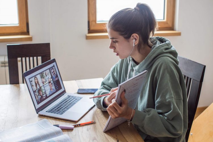 Teenager holding a notebook doing homework over Zoom