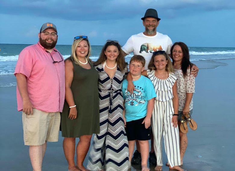 Family standing together on a beach smiling