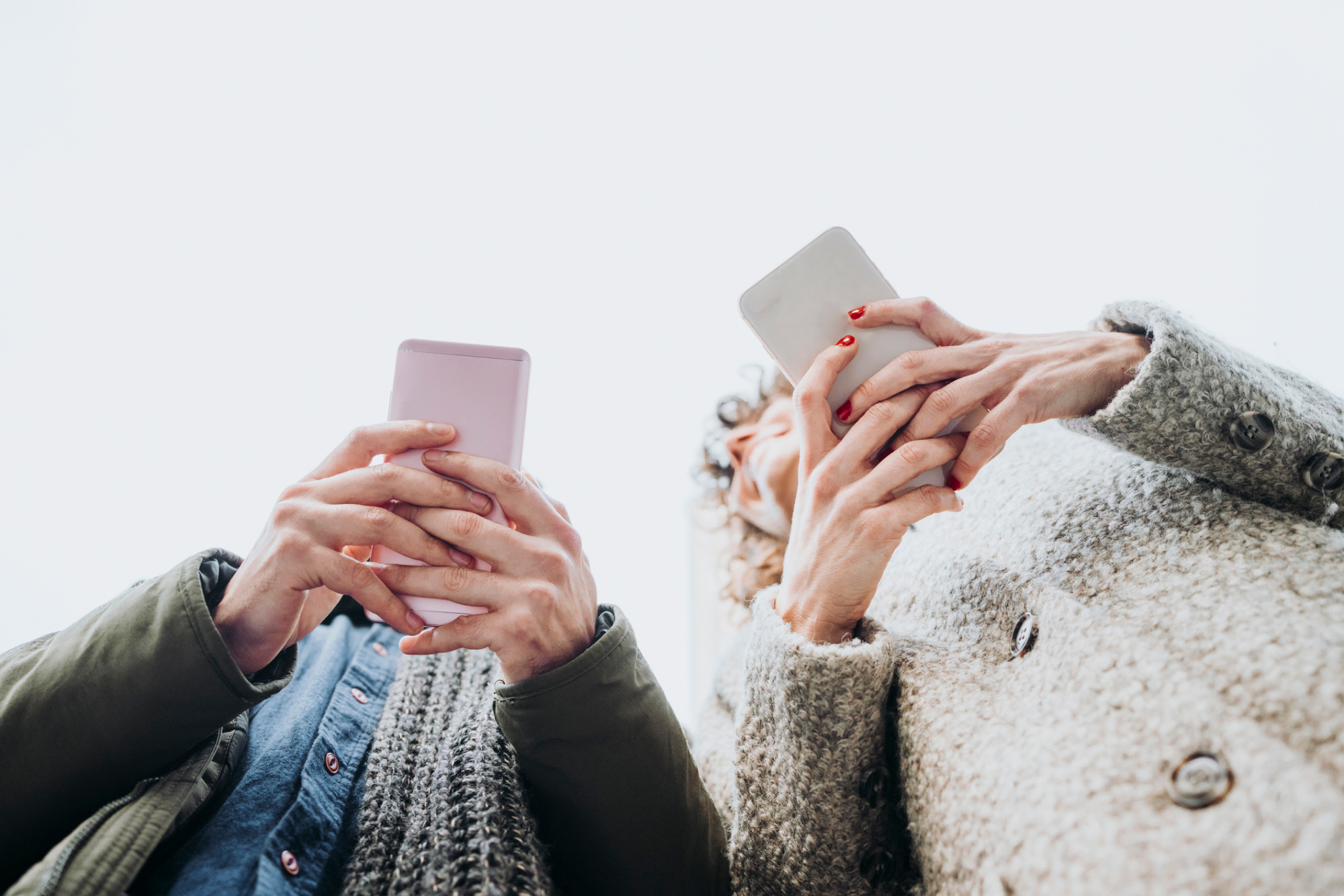 Two people holding their phones from a below angle shot