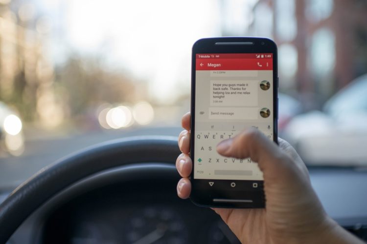 Driver of a car holding a phone and texting while driving