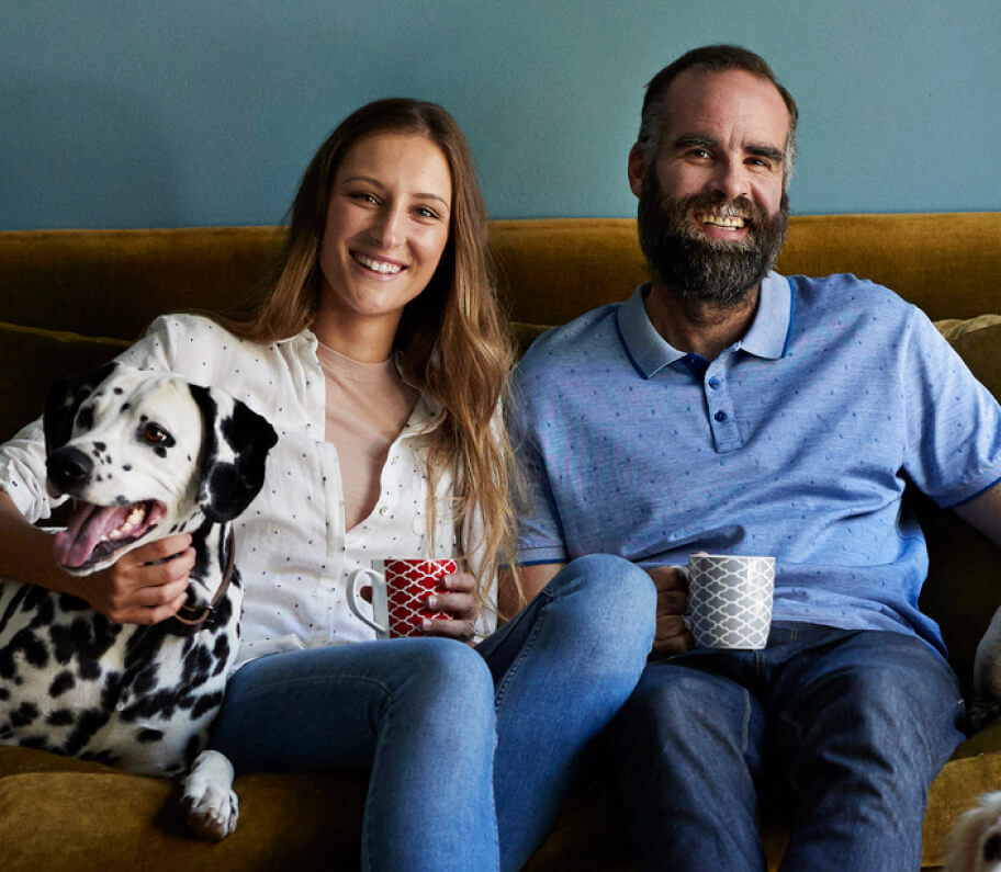 Parents sitting on couch with a Dalmatian dog