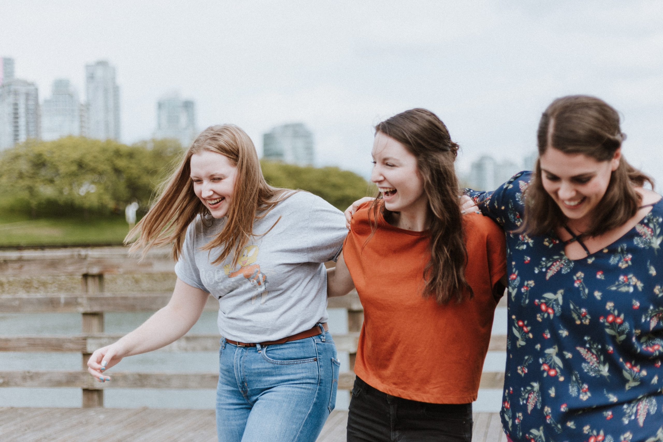 Three people walking and laughing with their arms around each other