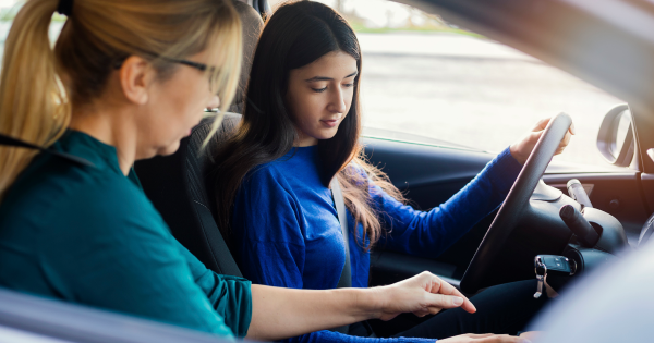 Mother teaching teen daughter to drive in a car