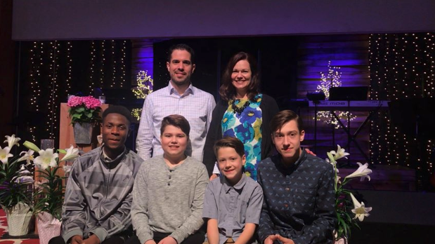 Family of 6 posing and smiling for a picture in a church