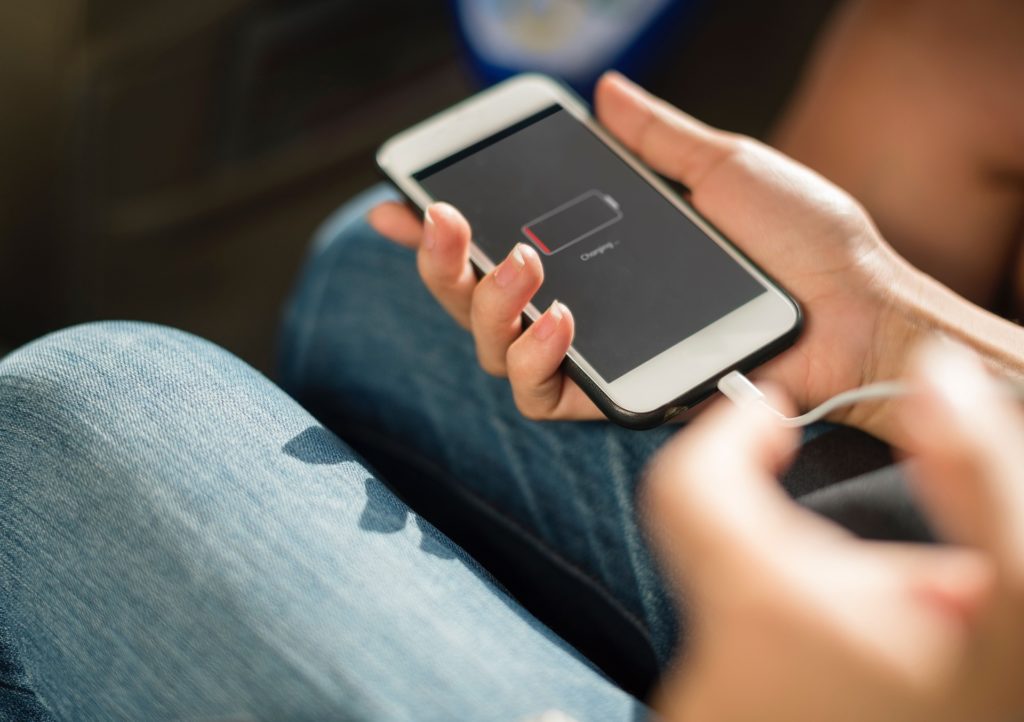 Person holding phone that has dead phone battery plugged into charger