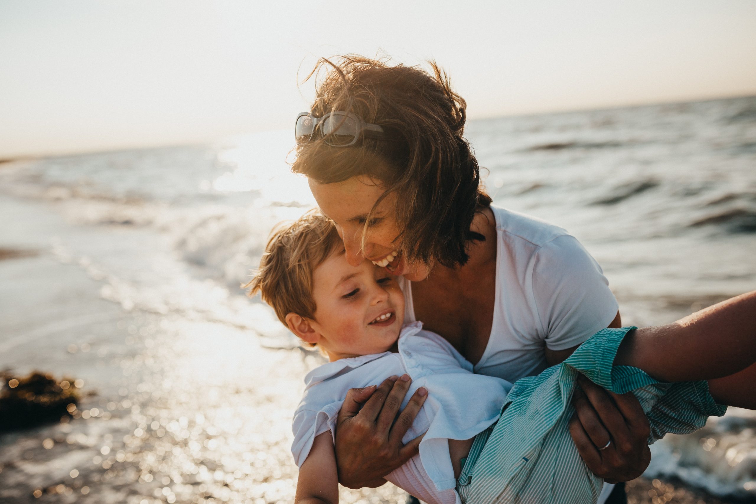 Mother laughing and holding young son at the beach