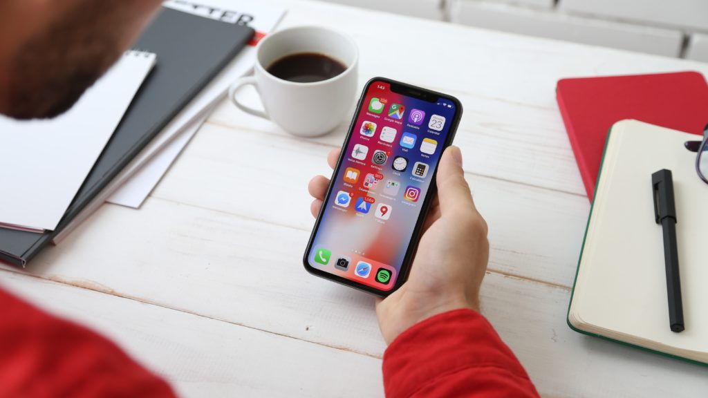 Person sitting at their desk holding their phone, showcasing apps.